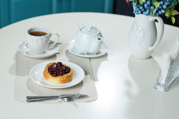 Danish with cherries and black tea on a table in a cozy coffee shop
