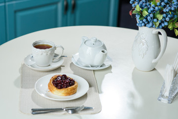 Danish with cherries and black tea on a table in a cozy coffee shop