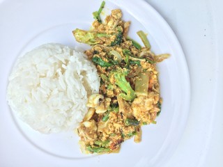 Stir fry mixed-seafood with with yellow curry powderin thai style with fried egg and rice in in white plate on white background.