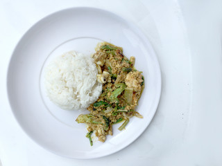 Stir fry mixed-seafood with with yellow curry powderin thai style with fried egg and rice in in white plate on white background.