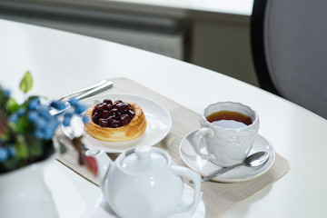 Fototapeta na wymiar Danish with cherries and black tea on a table in a cozy coffee shop