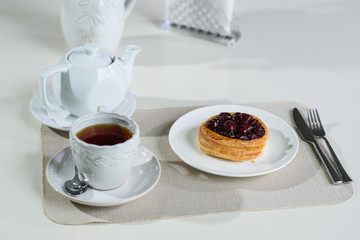 Danish with cherries and black tea on a table in a cozy coffee shop