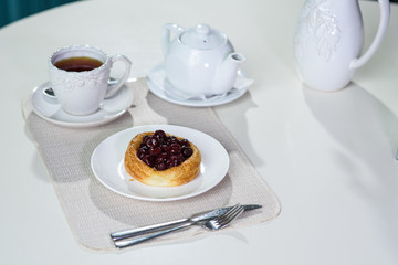 Danish with cherries and black tea on a table in a cozy coffee shop