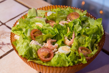 Tomatoes, shrimps, eggs and green salad in the plate on the table