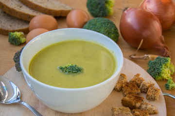 Close-up of healthy lunch, vegetable soup from broccoli, and bread, onion, eggs in the back, food on a wooden table, healthy eating