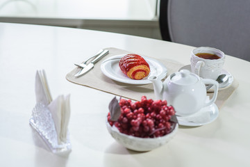 Cake with strawberries and black tea on the table in a cozy coffee shop
