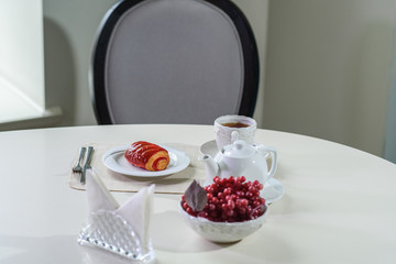 Cake with strawberries and black tea on the table in a cozy coffee shop