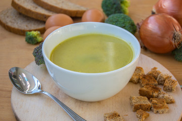 Close-up of healthy lunch, vegetable soup from broccoli, and bread, onion, eggs in the back, food on a wooden table, healthy eating
