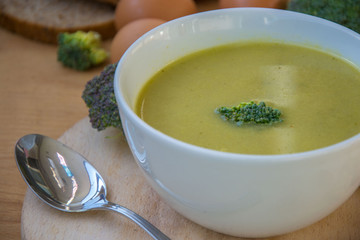Close-up of healthy lunch, vegetable soup from broccoli, and bread, onion, eggs in the back, food on a wooden table, healthy eating