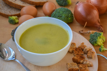 Close-up of healthy lunch, vegetable soup from broccoli, and bread, onion, eggs in the back, food on a wooden table, healthy eating