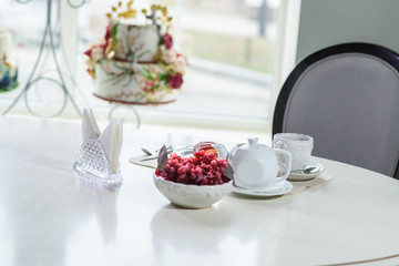 Cake with strawberries and black tea on the table in a cozy coffee shop