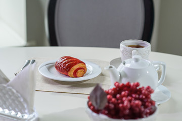 Cake with strawberries and black tea on the table in a cozy coffee shop