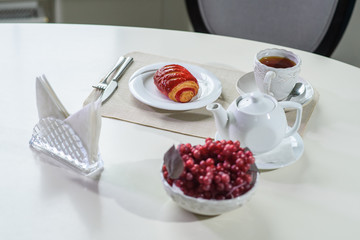 Cake with strawberries and black tea on the table in a cozy coffee shop