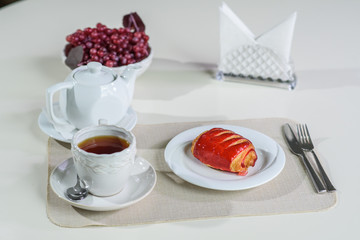 Cake with strawberries and black tea on the table in a cozy coffee shop