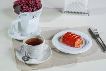 Cake with strawberries and black tea on the table in a cozy coffee shop