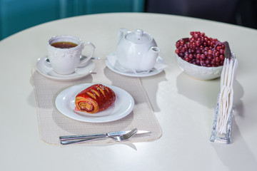 Cake with strawberries and black tea on the table in a cozy coffee shop