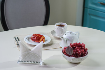 Cake with strawberries and black tea on the table in a cozy coffee shop