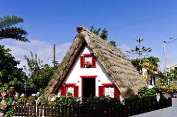 Fototapeta na wymiar Santana, Madeira, Portugal - 21 August 2019: a traditional white house of Santana with a thatched roof and red widows