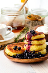 Cottage cheese pancakes and blueberries on a white wooden table, selective focus