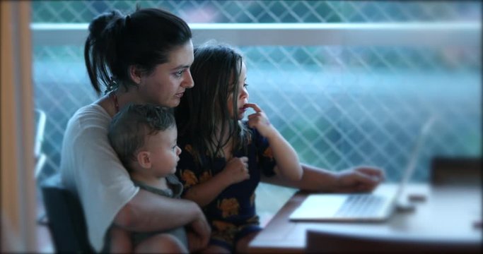 Authentic real life mother with children in front of computer laptop screen