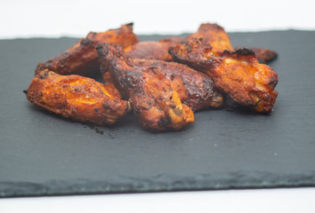 spicy chicken wings in the foreground on cast iron cooking.