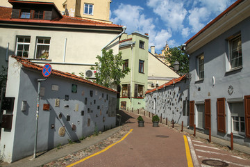 Fototapeta premium The small narrow street in Vilnius with some small artificial objects on the walls. 