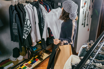 Woman shopping clothes. Shopper looking at clothing indoors in store. Beautiful happy smiling asian caucasian female model.