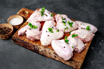 raw chicken wings on a cutting board with spices on a stone background 