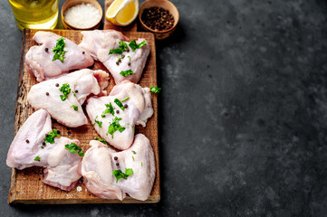 raw chicken wings on a cutting board with spices on a stone background with copy space for your text
