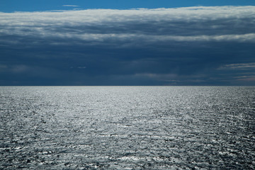 The Picture from a ferry between Sweden and Finland. The contrast between the dark cloudy sky and bright water with sun reflection.