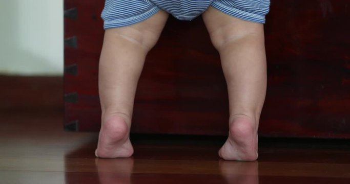 Baby little feet on tip toes. Toddler reaching and standing up