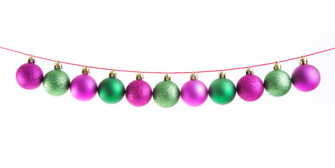 Line of green and purple christmas balls on white background. Christmas decorations.