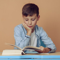 Caucasian boy reading book at the desk.