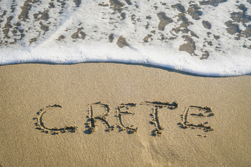 inscription Crete on the sand near the sea wave rest	