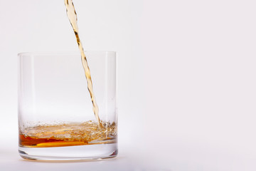 Close-up of an elegant glass for spirits, with a spilled liquor, similar to rum or whiskey, on a white background. There is a place for text.