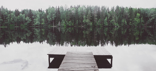 Empty pier of a beautiful lake.  Toned, atmospheric panoramic photo. The concept of the beauty of nature, peace, loneliness
