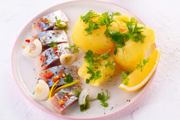 pieces of salted herring in spices with boiled potatoes