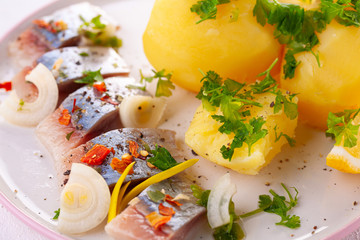 pieces of salted herring in spices with boiled potatoes