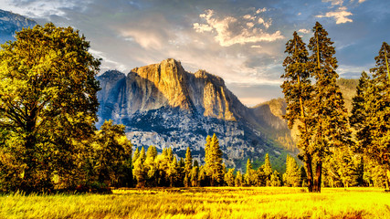 Setting Sun casting glowing sunlight over the almost dry Yosemite Upper Falls at Yosemite Point, the southern shoulder of the Half Dome granite rock in Yosemite National Park, California, USA