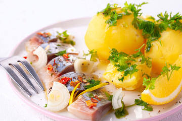 pieces of salted herring in spices with boiled potatoes