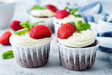 Chocolate cupcakes with cream cheese frosting, mint leaves and strawberries