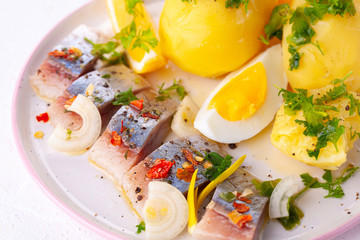 pieces of salted herring in spices with boiled potatoes