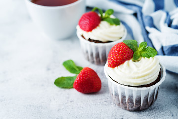 Chocolate cupcakes with cream cheese frosting, mint leaves and strawberries