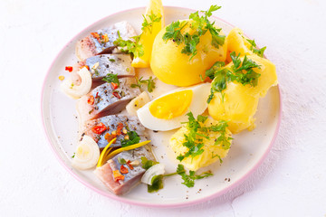 pieces of salted herring in spices with boiled potatoes
