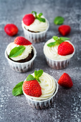 Chocolate cupcakes with cream cheese frosting, mint leaves and strawberries