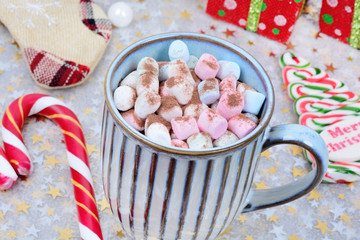 Hot chocolate in a mug with colorful marshmallow and christmas ornament on shiny table