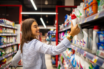 Pretty young woman buying groceries in a supermarket/mall/grocery store. Beautiful brunette looking at some shelves in a supermarket trying to decide what to buy