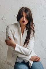 Beautiful young woman wearing white blazer and blue jeans