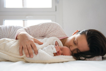 Obraz na płótnie Canvas Mother cuddling with her new born baby