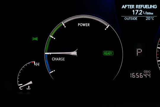 The dashboard of the car is glowing white with arrows at night with a speedometer, charge battery level and other tools to monitor the condition of the hybrid vehicle in modern style on black - Powered by Adobe